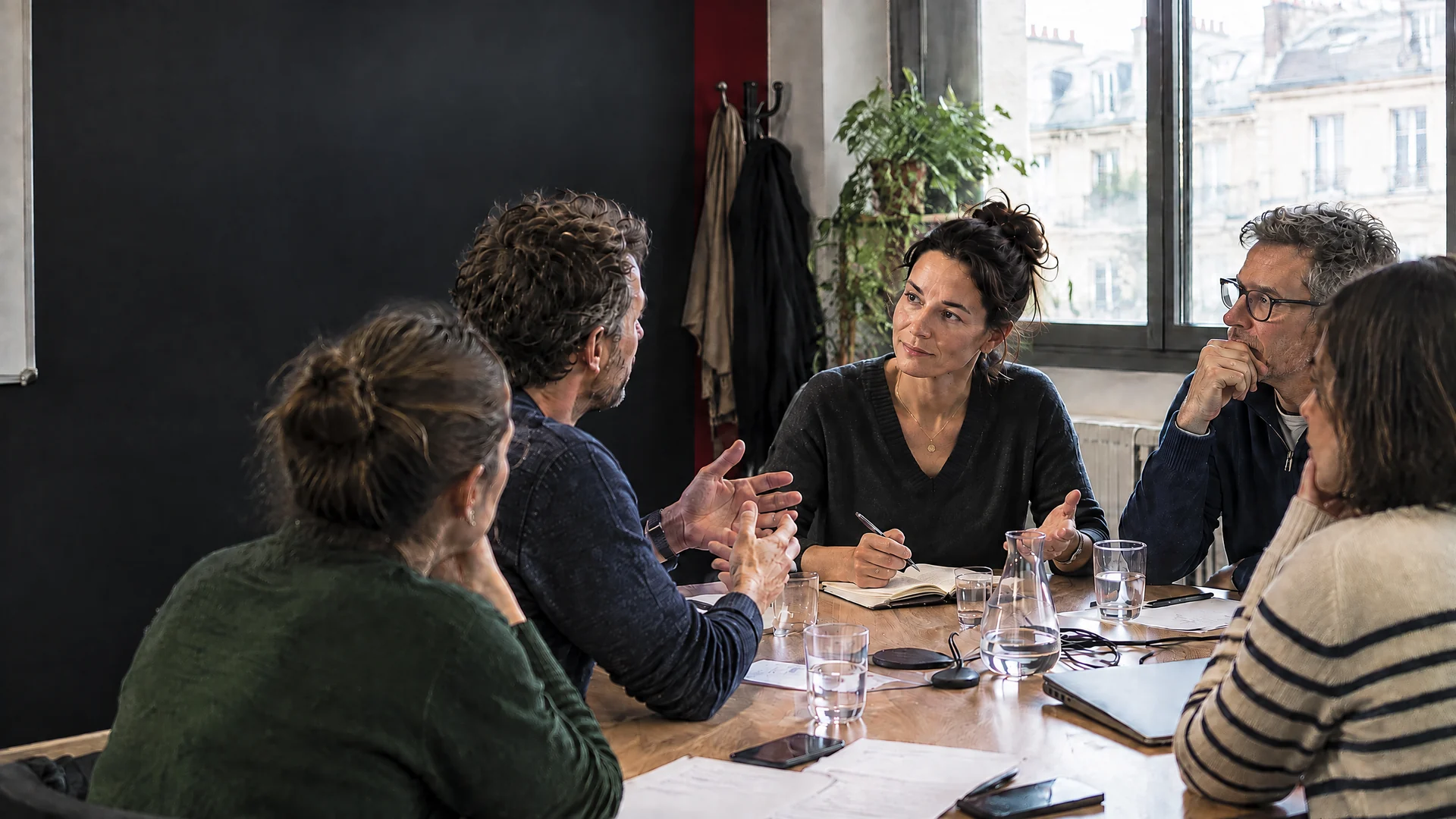 Une nouvelle manager échange avec ses anciens collègues autour d’une table de réunion.